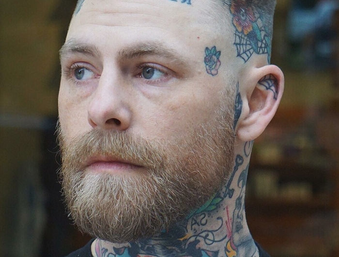 mann mit vielen farbigen tattoos kurzer haarschnitt seiten auf null mit üergang herren kurzhaarfrisuren mit bart dunkelblonde haare