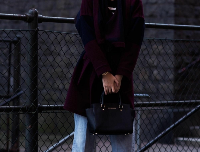 stylishes outfit inspiration langer violetter mantel hellblaue jeans damen kleine schwarze handtasche