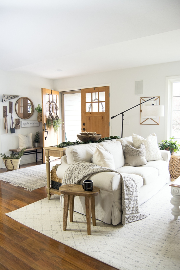 wohnzimmer skandinavischer stil bode und tür aus holz weißes sofa mit vielen kissen hygge style einrichtung