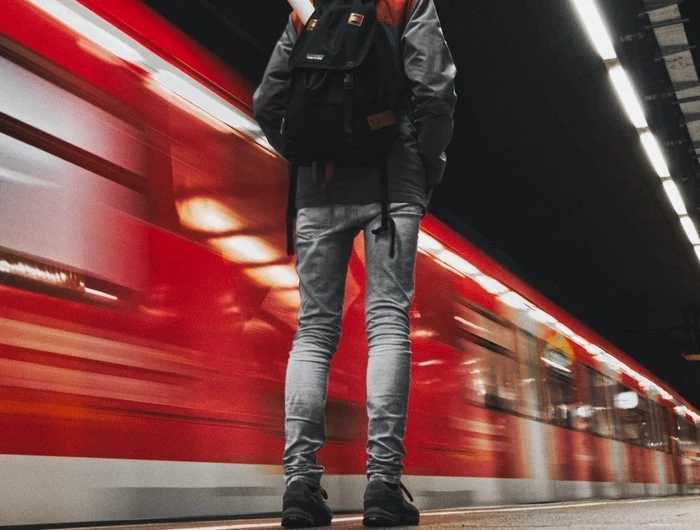 mit dem zug fahren reisen geschichte mann am bahnsteig roter zug vorbeifahren