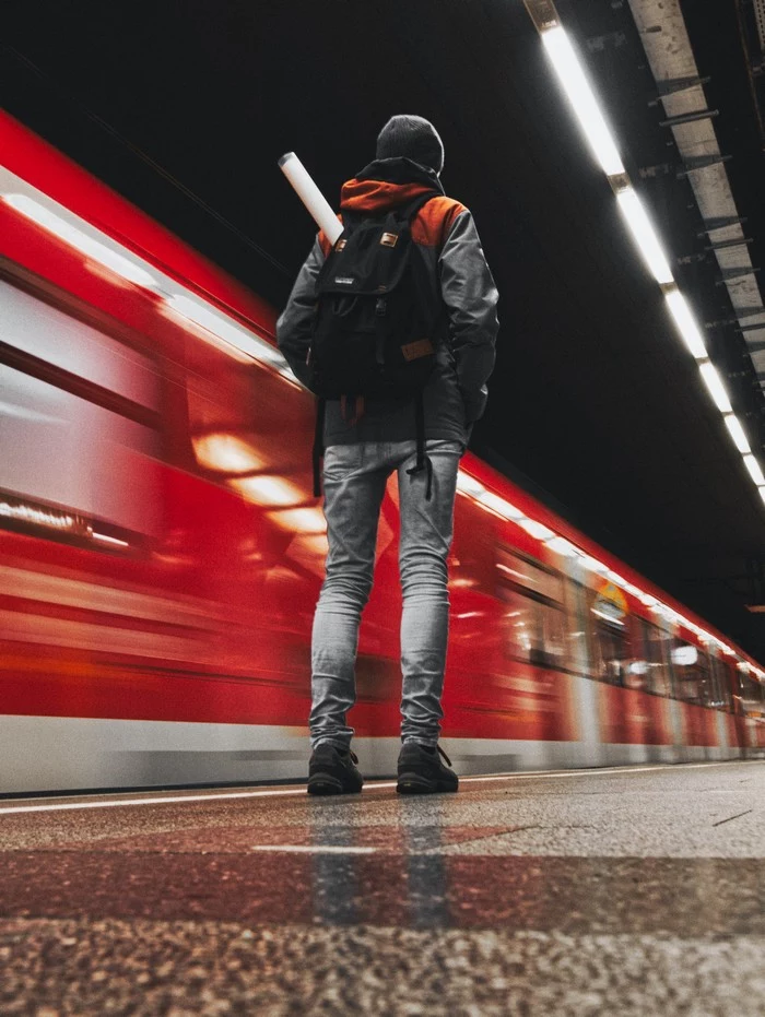 mit dem zug fahren reisen geschichte mann am bahnsteig roter zug vorbeifahren