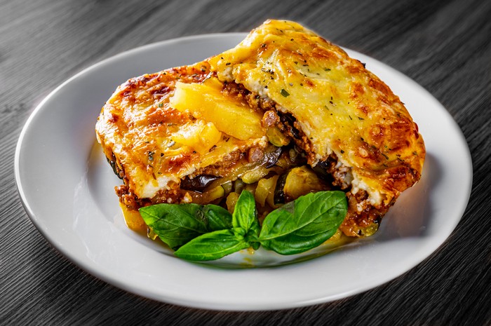 traditional greek moussaka in white plate on black wooden table background