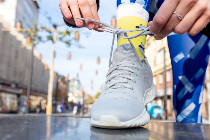 sporty woman tying shoelace on sneakers before training. female athlete preparing for jogging outdoors.
