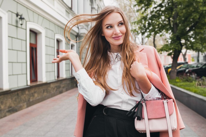 cute attractive stylish smiling woman walking city street in pink coat spring fashion trend holding purse, elegant style