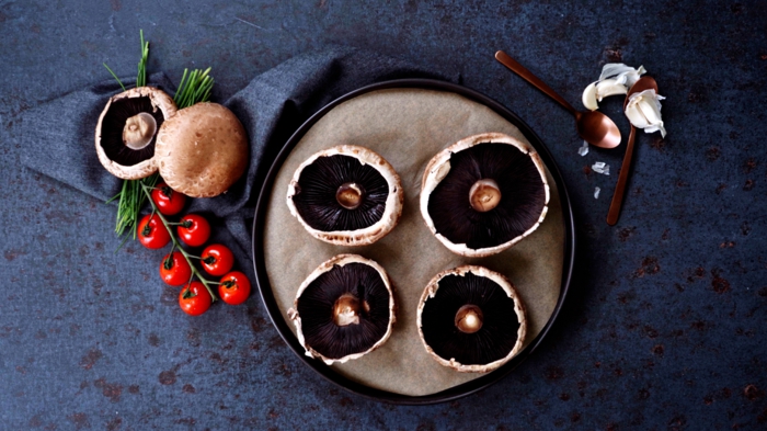 kleine löffel und rote tomaten gefüllte portobello pilze rezept teller mit pilzen