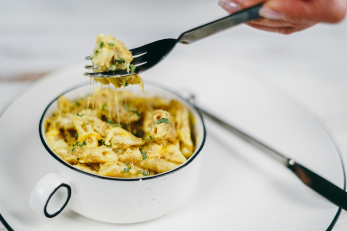 amerikanische mac and cheese rezept eine hand mit gabel mit penne pasta