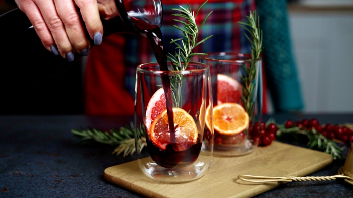 ein holzbrett zwei gläser mit rotwein und geschnittenen zitronen und orangen