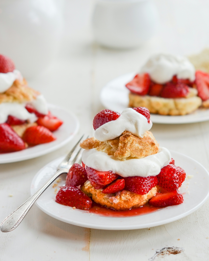 gabel und weiße teller dessert mit sahne und erdberen selber machen frische rote erdbeeren