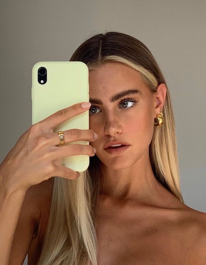 90 er trends in 2021 lange braune haare blonde strähne vorne goldener schmuck ohrringe frau macht selfie welche haarfarbentrends sind 2021 angesagt