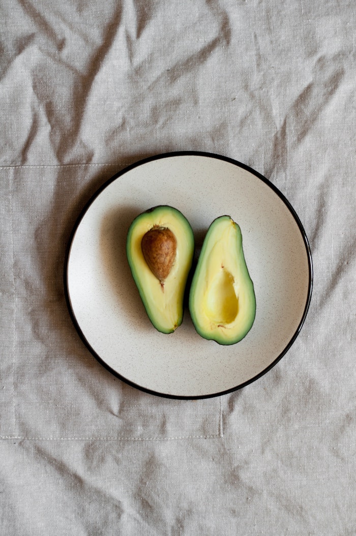 guacamole rezept ein weißer teller mit einer geschnittenen friaschen grünen avocado eine avocado schneiden