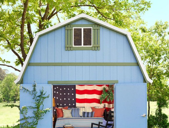 blaues kleines gartenhaus umgewandelt in einem zimmer große amerikanische flagge großes bett bunte deko kissen