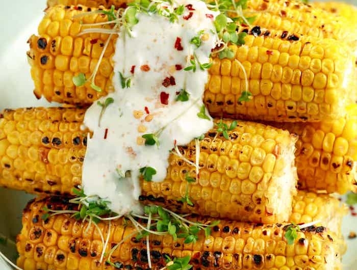 eine weiße schüssel mit maiskollben mexikanische gerichte mit gegrilltem und gegkochtem maiskolben und mayo und gewürzen