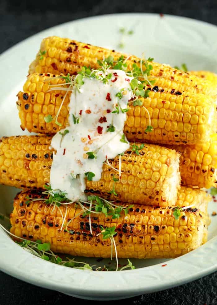 eine weiße schüssel mit maiskollben mexikanische gerichte mit gegrilltem und gegkochtem maiskolben und mayo und gewürzen