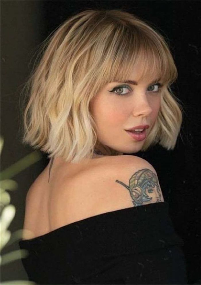 frau mit einem tattoo am arm kurze blonde gewellte haare mit pony haarfrisuren inspirationbob dünnes haar schwarze bluse style