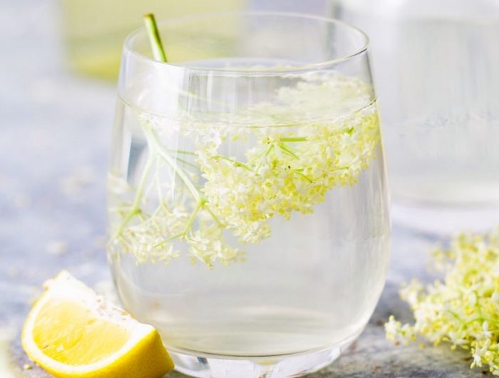 glas mit frischem holunderblütensirup ohne zucker eine gelbe geschnittene zitrone