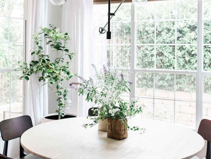 grüne pflanzen dekoration wohn esszimmer schwarze moderne stühle massiver runder tisch aus holz interior design inspiration