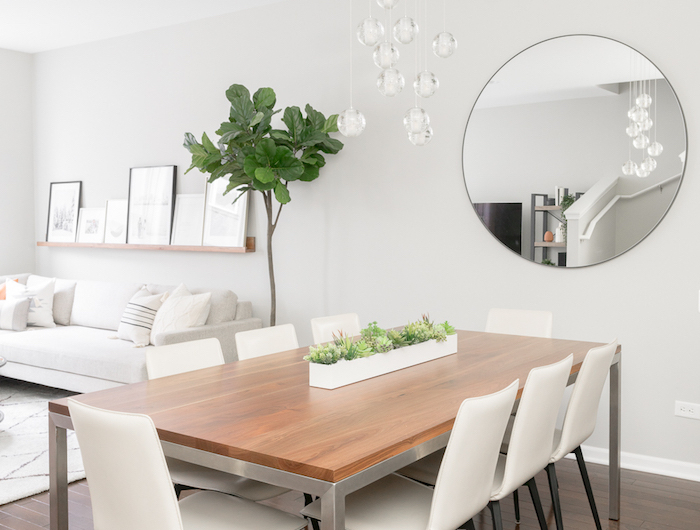minimalistische inneneinrichtung in weiß kombiniertes wohn esszimmer einrichten großer runder spiegel grüne pflanze moderne einrichtung esszimmer dunkler holzboden