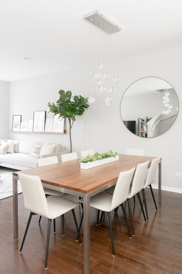 minimalistische inneneinrichtung in weiß kombiniertes wohn esszimmer einrichten großer runder spiegel grüne pflanze moderne einrichtung esszimmer dunkler holzboden