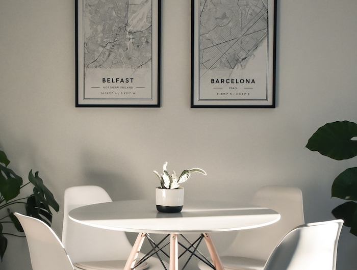 monochrome minimalistische einrichtung kleiner runder tisch mit vier stühlene bilder an die wand mit karten von belfast und barcelona wohn esszimmer einrichten