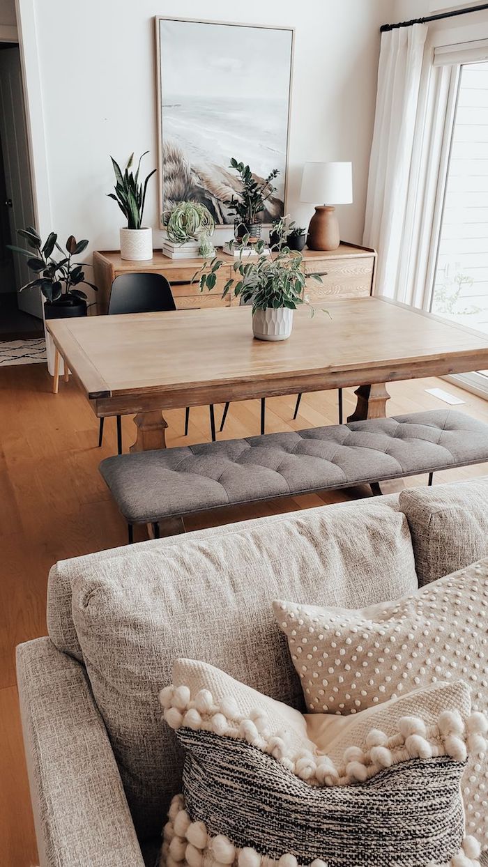 offenes konzept wohnzimmer mit essbereich minimalistische farben holz motive grüne pflanzen großes gemälde vom strand