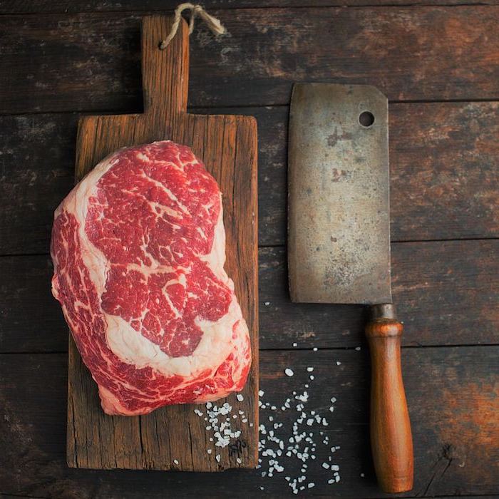 rib eye steak entrecote zubereitung rinder entrecote fleisch rib eye steak mit knoblauchsoße rohes rib eye steak groß auf schneidebrett hackmesser