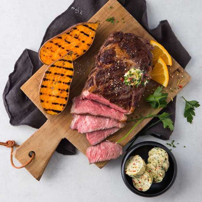 ribeye grillen steak entrecote zubereitung t bone steak großes stück ribeye gebratene süße kartoffel orange auf schneidebrett
