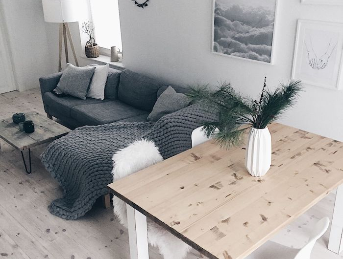 skandinvische einrichtung minimalistisch kombiniertes wohn esszimmer einrichten grauer ecksofa flauschige decke und kissen heller holztisch weiße stühle kreative wandgestaltung wohnzimmer