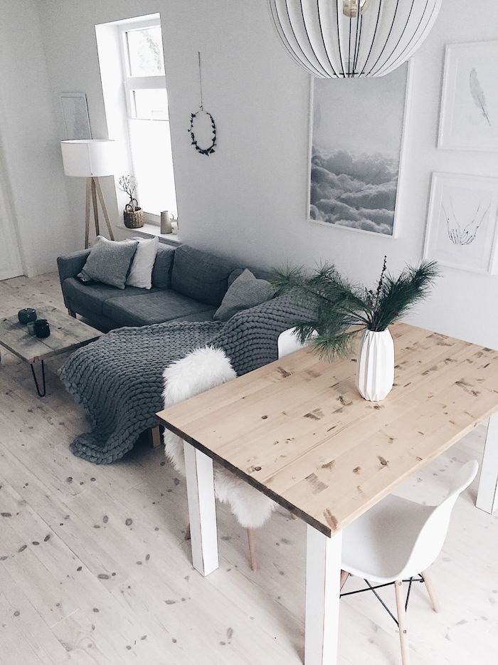 skandinvische einrichtung minimalistisch kombiniertes wohn esszimmer einrichten grauer ecksofa flauschige decke und kissen heller holztisch weiße stühle kreative wandgestaltung wohnzimmer