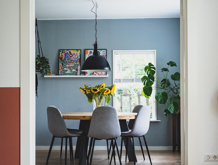 stylische esszimmer ideen kleine wohnung einrichten runder tisch aus holz graue stühle grau blaue wandfarbe große grüne pflanze sonnenblume in vase