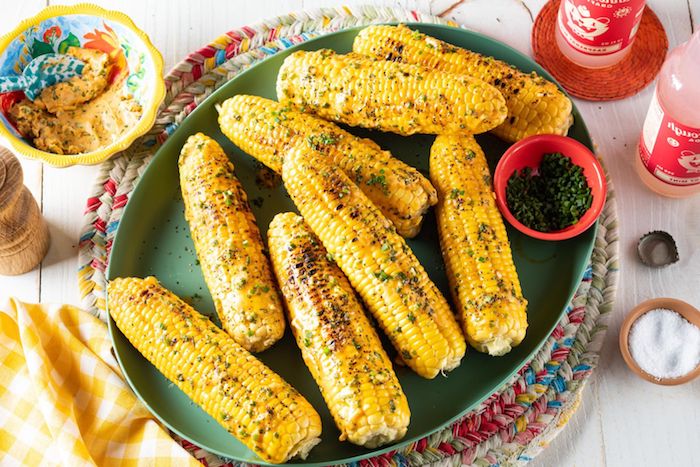 viele gesürze gekochte maiskolben mit käse petersilie gewürzen und scharfen roten paprikas große roet maiskolben eine gelbe decke