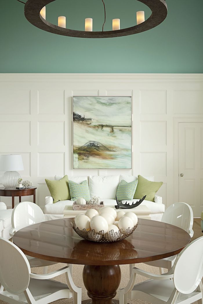 wandfarbe weiß grün wohnzimmer mit essbereich runder tisch aus holz weiße stühle weißes sofa mit grünen und weißen kissen moderne inneneinrichtung