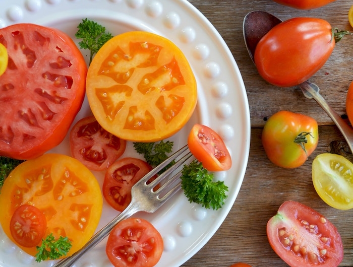 weißer teller mit geschnittenen roten tomaten ein tisch aus holz rote tomaten salat zum grillen schnell gemacht