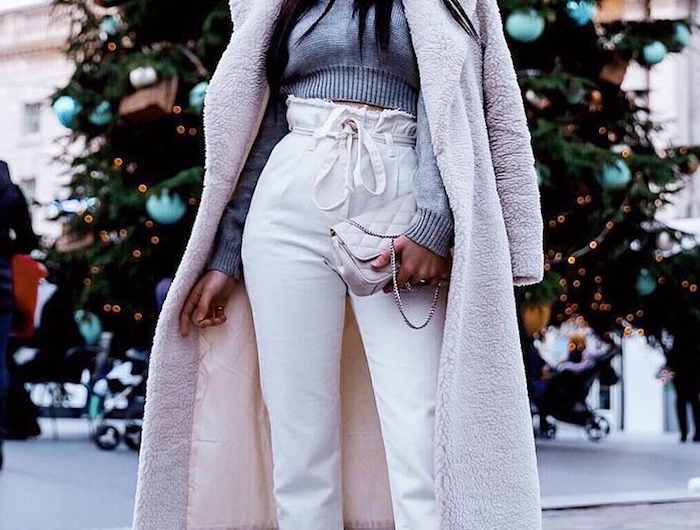 winter outfit weißer flauschiger mantel graue gecroppte bluse was ist eine paperbag hose sportliche sneaker großer tannenbaum im hintergrund