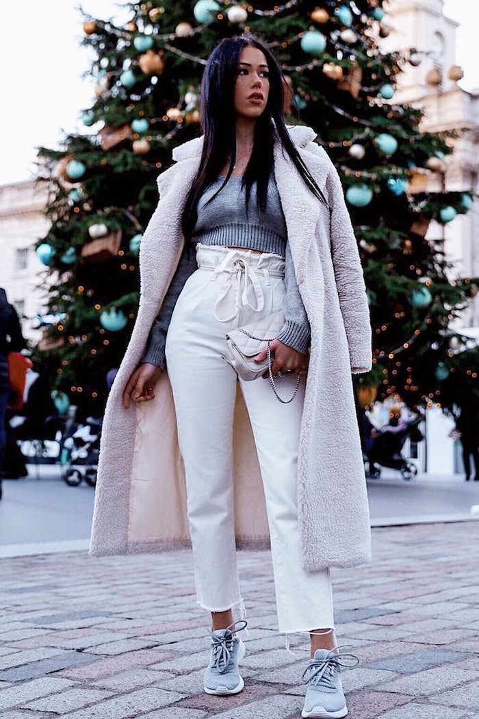 winter outfit weißer flauschiger mantel graue gecroppte bluse was ist eine paperbag hose sportliche sneaker großer tannenbaum im hintergrund