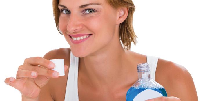hausmittel gegen zahnschmerzen was tun bei zahnschmerzen kieferentzündung frau lächelt hält flasche mundpflege mundspülung
