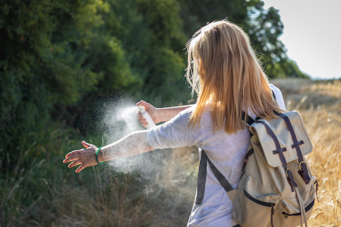 woman tourist applying mosquito repellent on hand during hike in nature. insect repellent.
