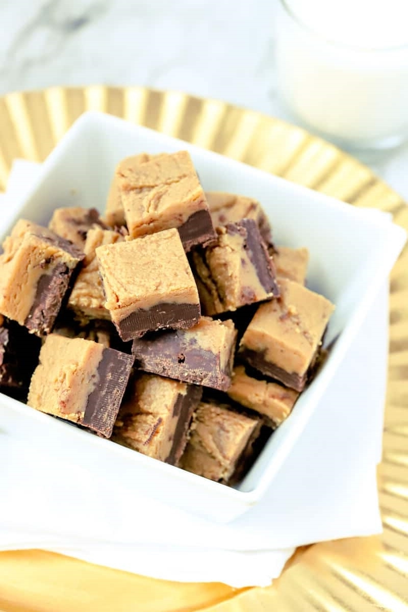 chocolate peanut butter fudge in white square bowl on gold tray