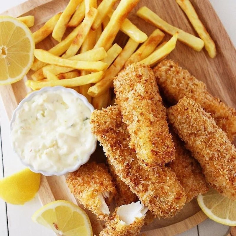 beilage fischstäbchen pommes mayonnaise und zitronen auf holzbrett