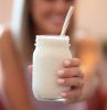hafermilch vitamine eine frau trinkt hafermilch in glas mit stroh