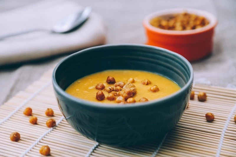 kichererbsensuppe mit kokosmilch in dunkelblauer schüssel auf dem tisch