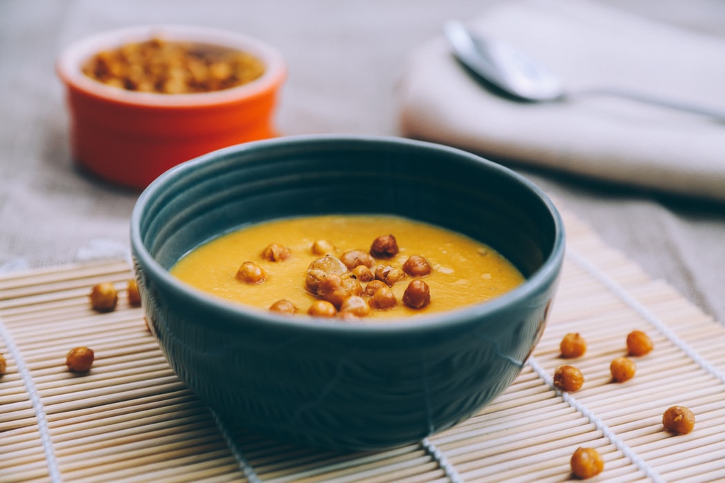 kichererbsensuppe mit kokosmilch in dunkelblauer schüssel auf dem tisch