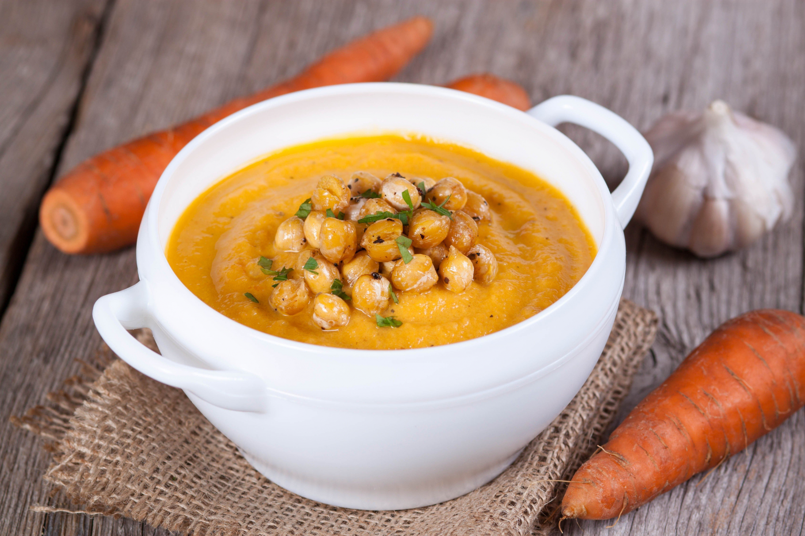 kichererbsensuppe mit möhren cremesuppe im weißen topf auf dem holztisch