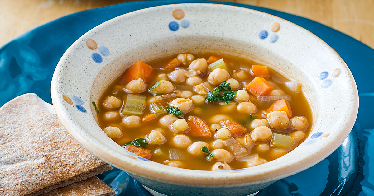 kichererbsensuppe mit möhren und gemüsebrühe in schüssel auf blauem teller