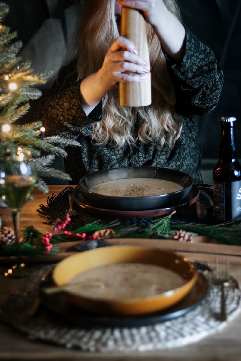 persische kräutersuppe eine dame würzelt ihre suppe auf dem tisch