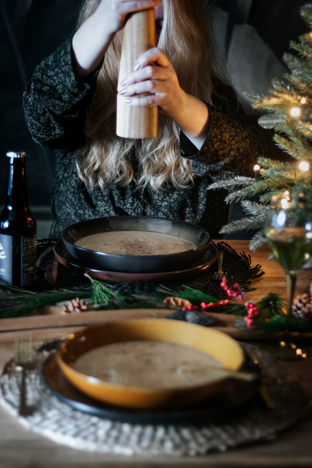 persische kräutersuppe eine dame würzelt ihre suppe auf dem tisch