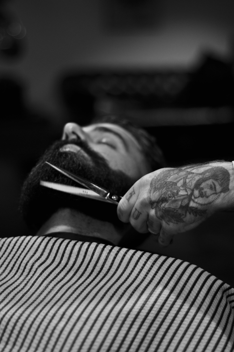 eine hand mit tattoo schwarzer bart ducktail bart selber schneiden hand mit schere