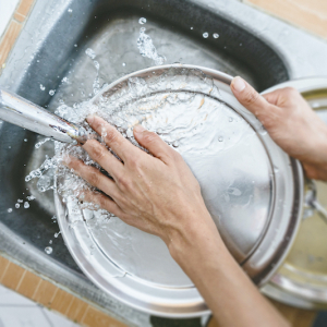 cropped hands of woman washing dishes in kitchen sink