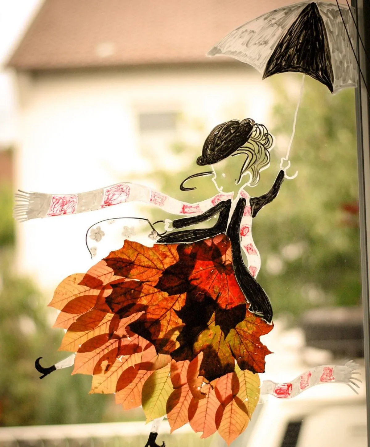 herbstliche fenster deko frau mit rock aus herbstblättern und regenschirm