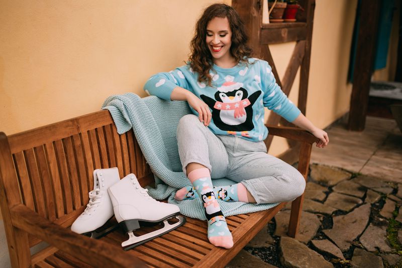 geschenk für eltern weihnachtsgeschenke für eltern frau sitzt an einer bank pullover mit pinguin hellblau schlittschuhen