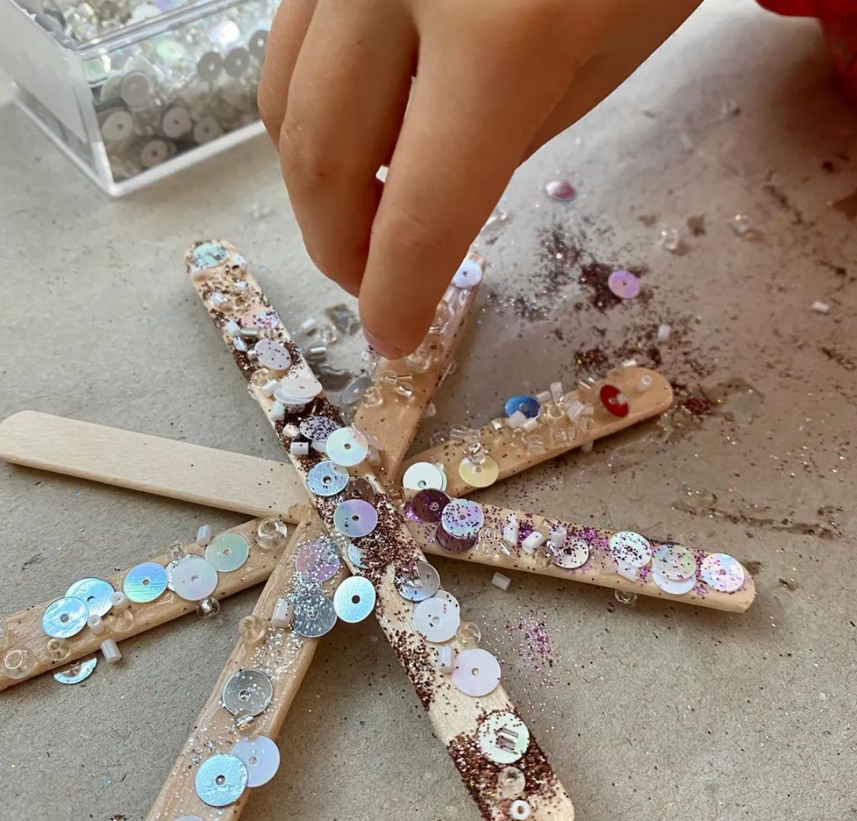 schneeflocke aus eisstäbchen mit knöpfen und glitzer bekleben